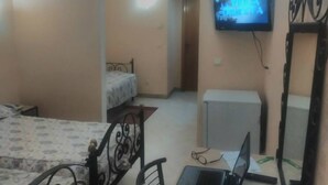 A bedroom with a bed, a desk with a laptop, and a television on the wall. - Ariha Hotel (Tunis)
