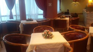 A dining area with round wooden tables, some with floral centerpieces. - Ariha Hotel (Tunis)