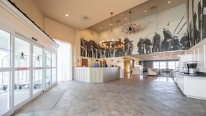 A spacious lobby with a reception desk, large windows, and a mural of workers. - AmishView Inn and Suites (Ronks)