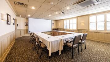 A conference room with a long table, chairs, a projector screen, and large windows.