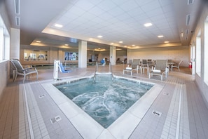 A large indoor swimming pool with multiple seating areas and a reception desk in the background.