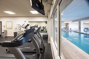 A gym with treadmills and a pool area.