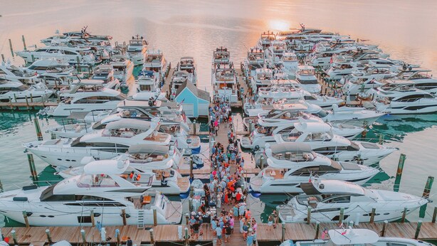 A marina with numerous boats docked, a wooden pier, and a sunset in the background. - Valentines Resort & Marina (Dunmore Town)