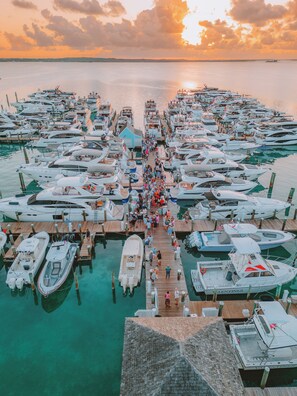 A marina with numerous boats docked, a wooden pier, and a sunset in the background. - Valentines Resort & Marina (Dunmore Town)