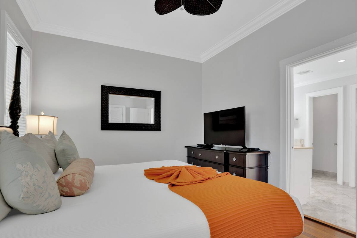A bedroom with a bed, a dresser, a television, and a mirror.