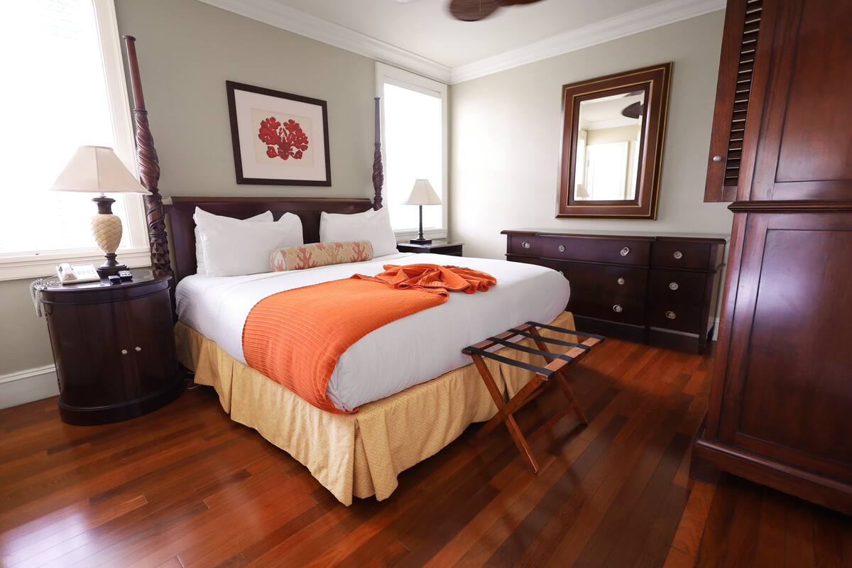 A bedroom with a bed, nightstands, a dresser, a mirror, and a window.