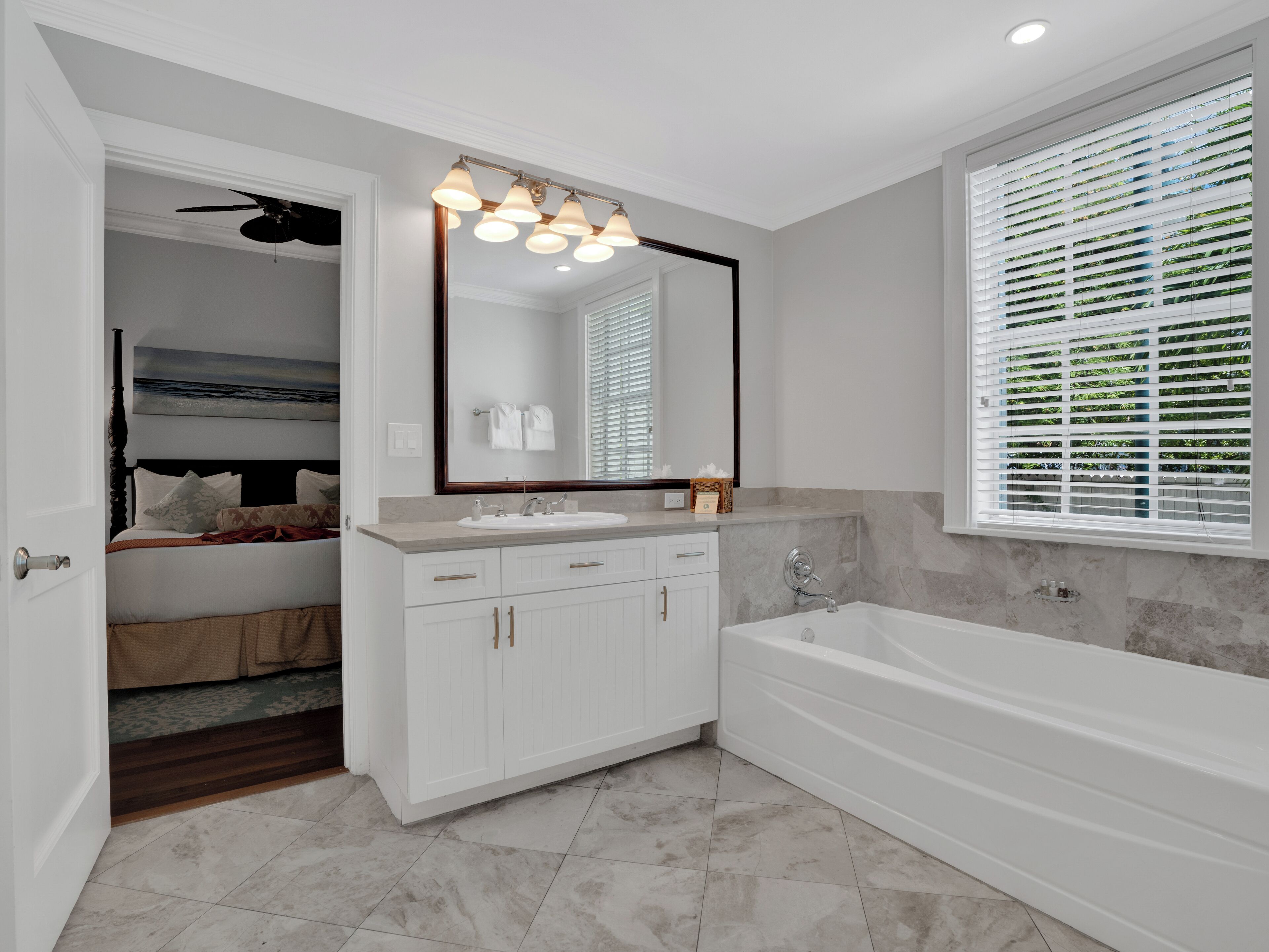 A modern bathroom with a large mirror, a bathtub, and a vanity with a sink.