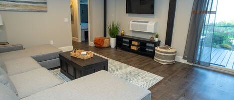 Una sala de estar moderna con un sofá modular, una mesa de centro y un televisor de pantalla plana montado en la pared.