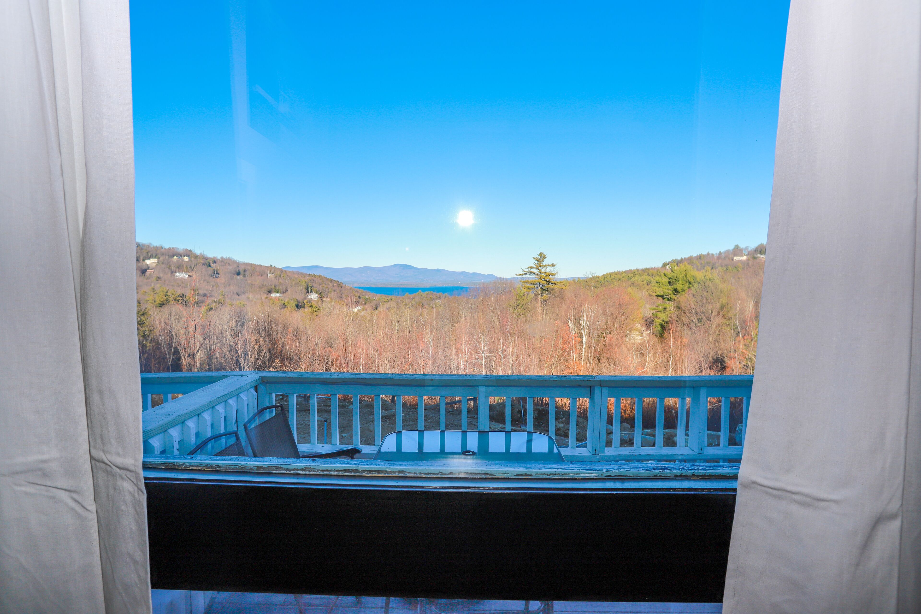 A view from a balcony with a railing, overlooking a landscape with trees and mountains in the distance.