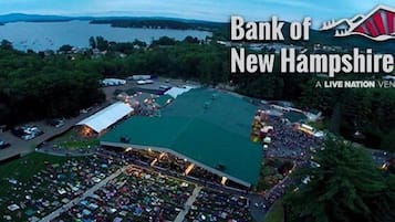 Vista aérea del Pabellón Bank of New Hampshire, recinto de Live Nation con un amplio campo central rodeado de estacionamiento y edificios.