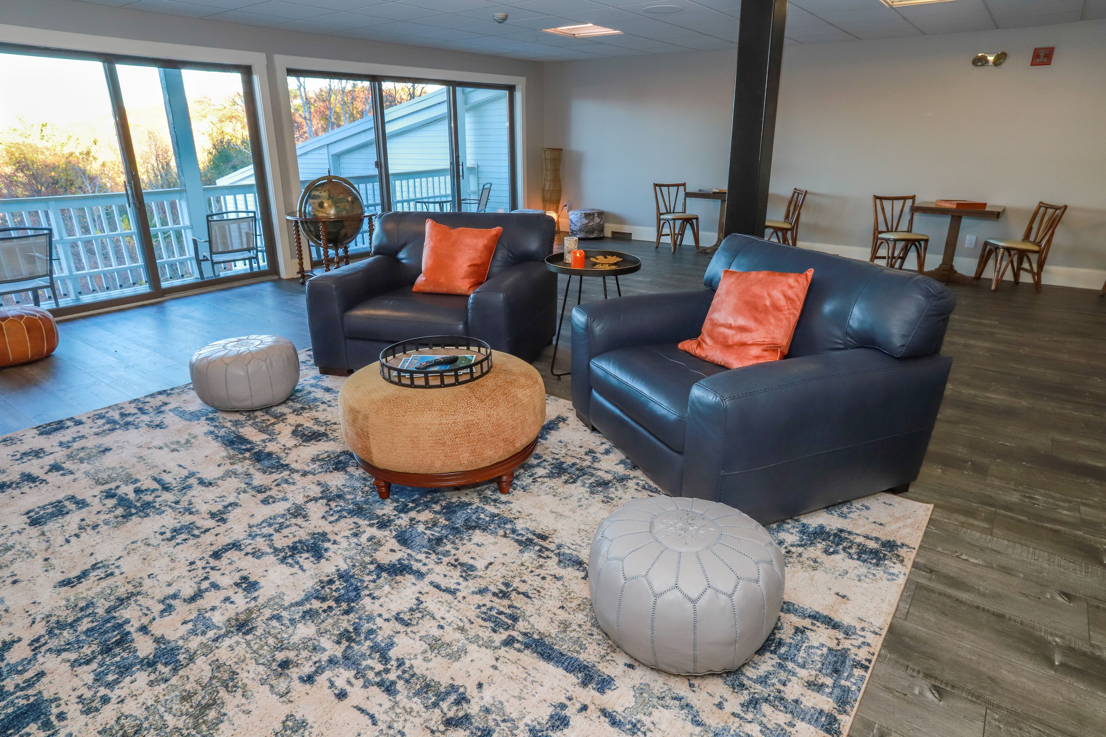 A spacious lounge area with leather sofas, ottomans, and a large rug.