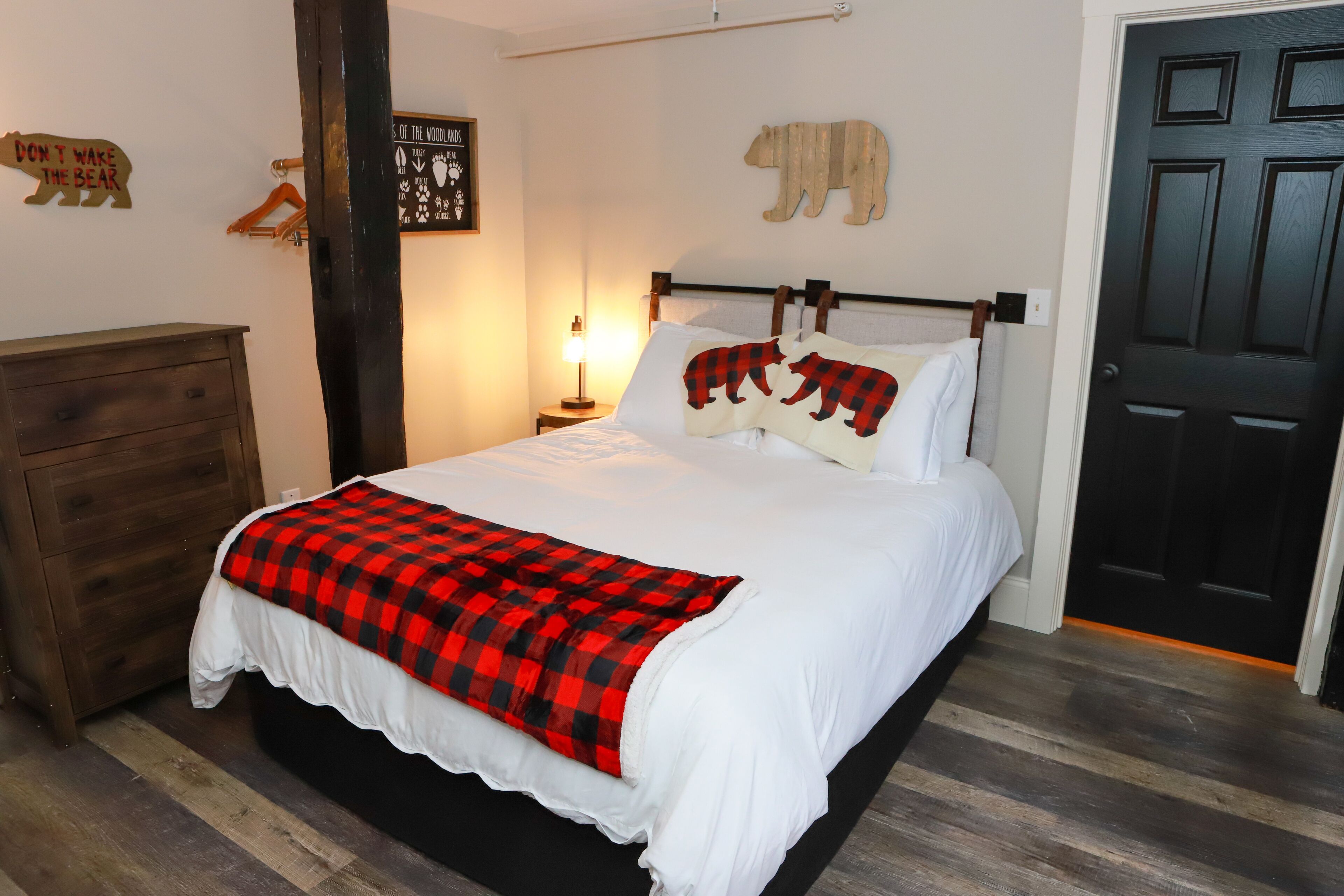 Un dormitorio con cama, cómoda, lámpara de pared y puerta.