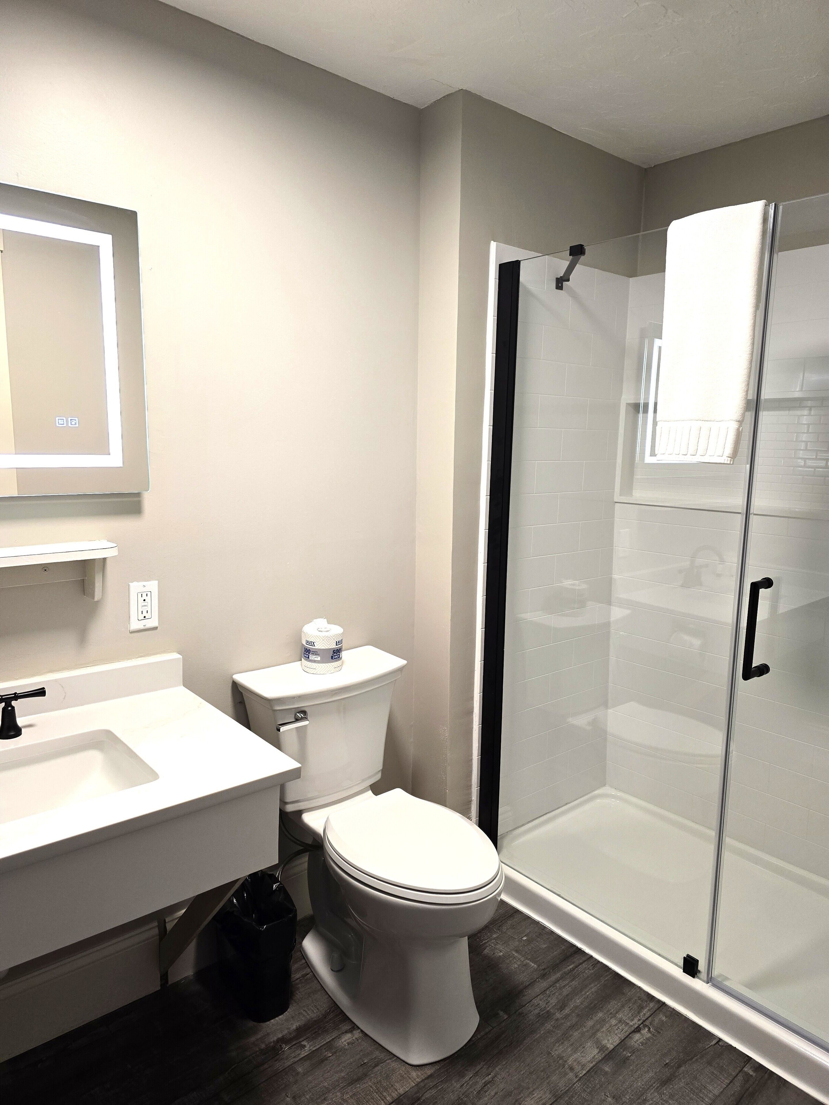 A modern bathroom with a toilet, sink, and glass shower enclosure.