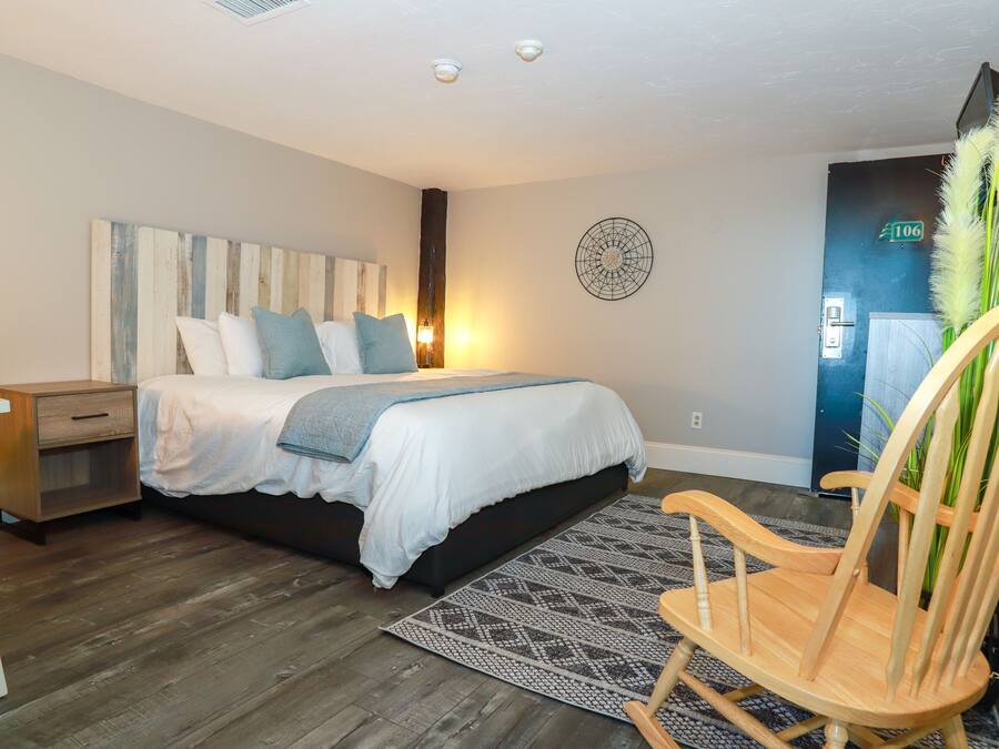 Un dormitorio con cama, mesita de noche, silla y un cuadro decorativo en la pared.