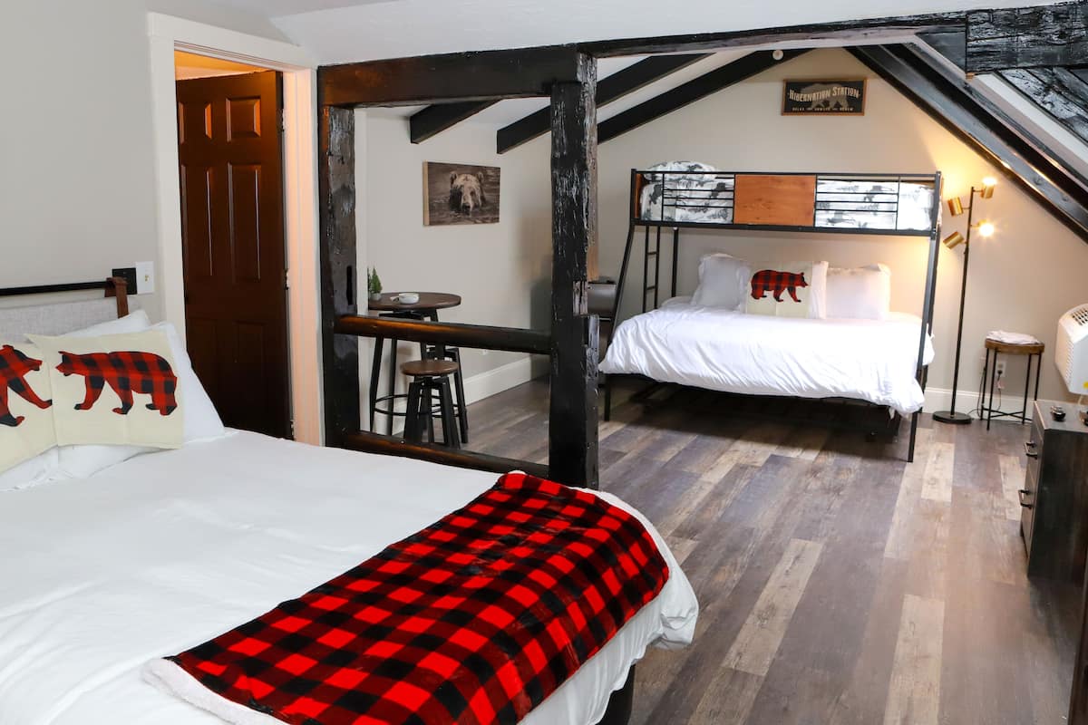 A bedroom with two beds, a wooden ceiling, a small table, and a chair.