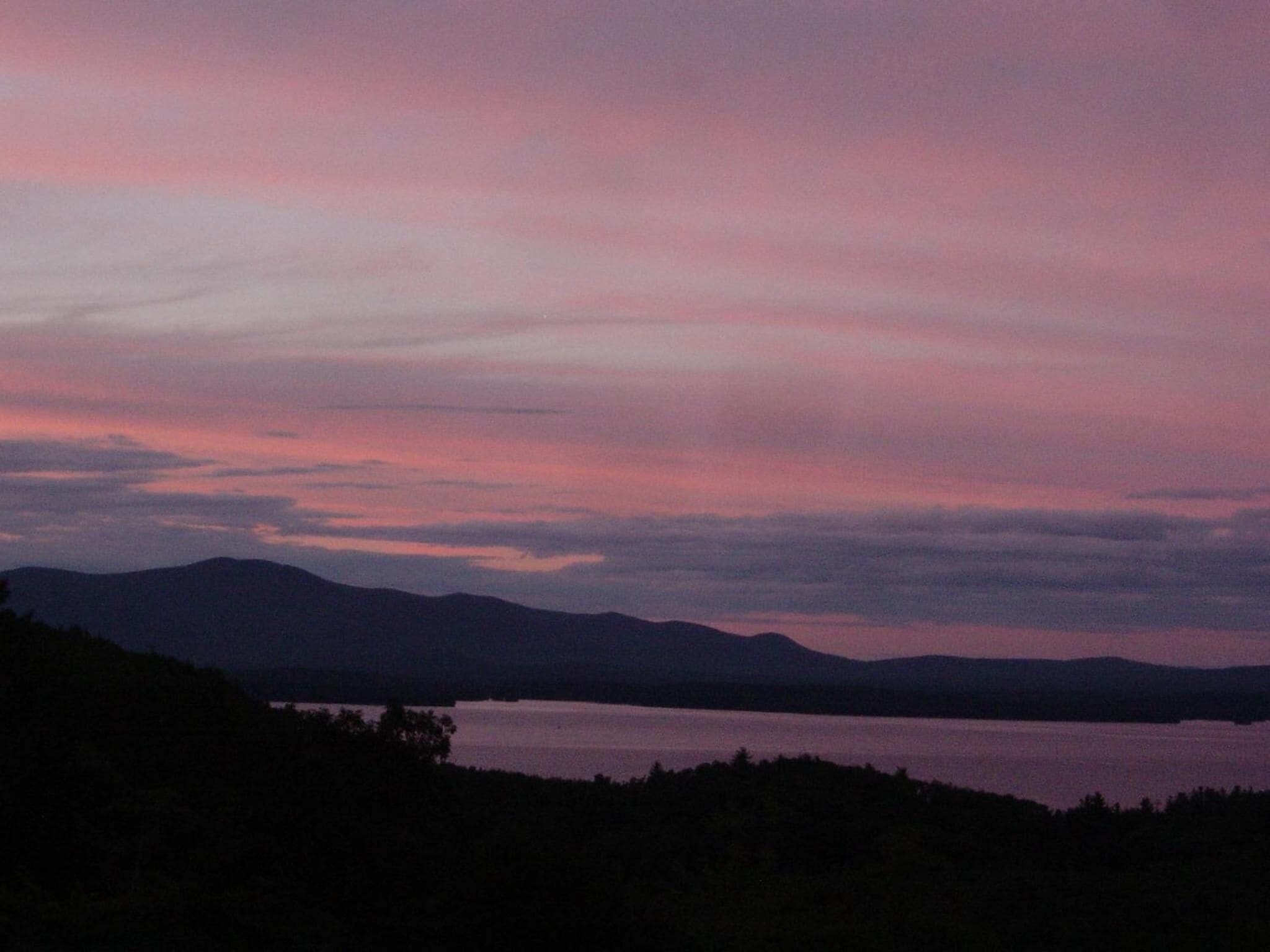 A landscape with mountains and a body of water during twilight.