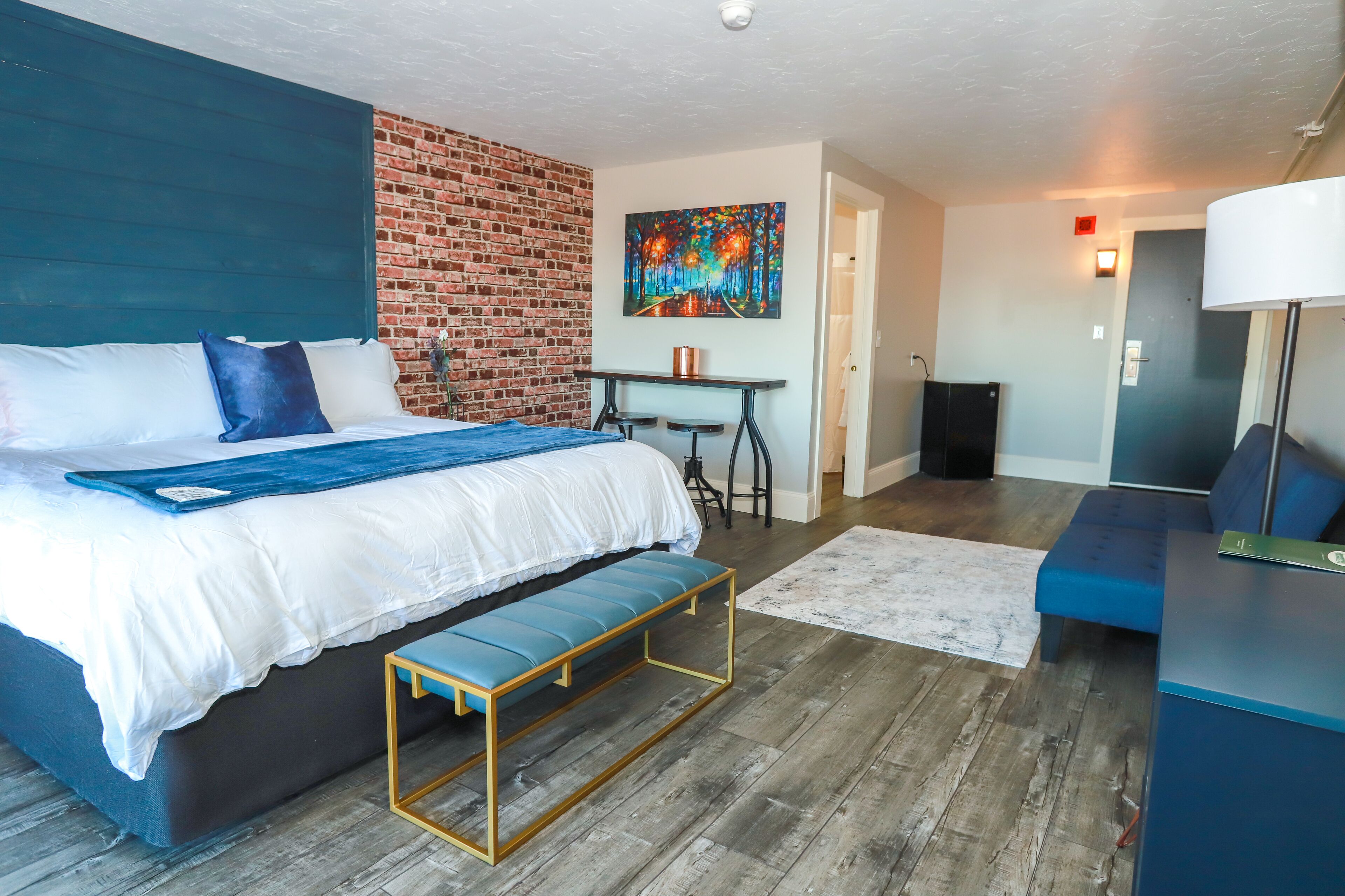 Une chambre d’hôtel moderne avec un grand lit, une banquette, un bureau et un tableau au mur.