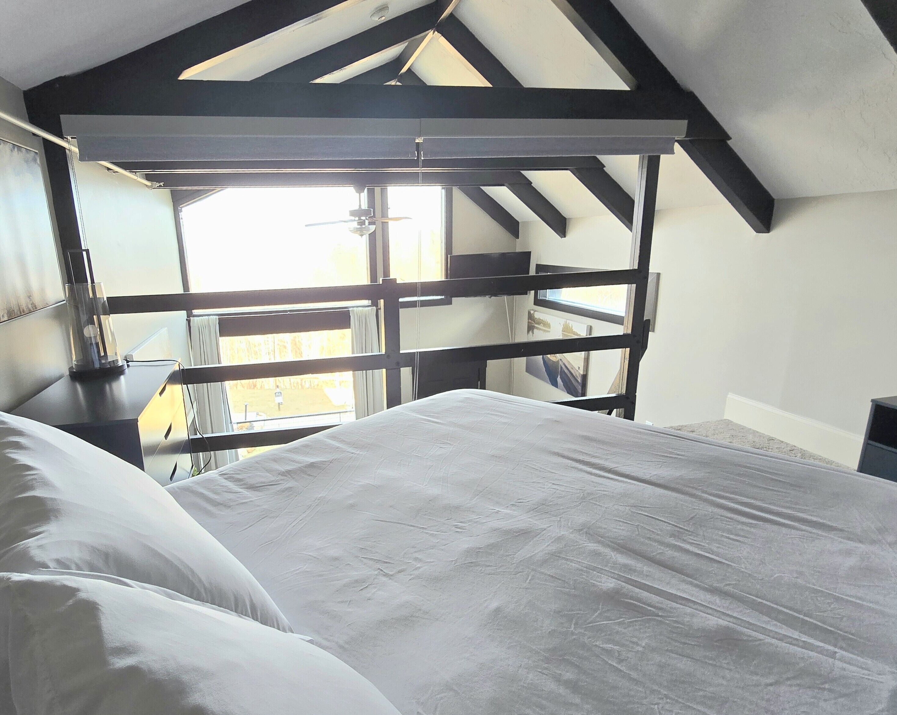 A bedroom with a bed, a window, and a view of the outside.