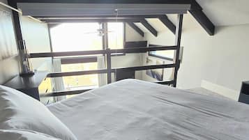 A bedroom with a bed, a window, and a view of the outside.