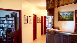 A hallway with a wooden bookshelf, framed pictures on the wall, and a painting. - Hotel Vogar (Vogar)