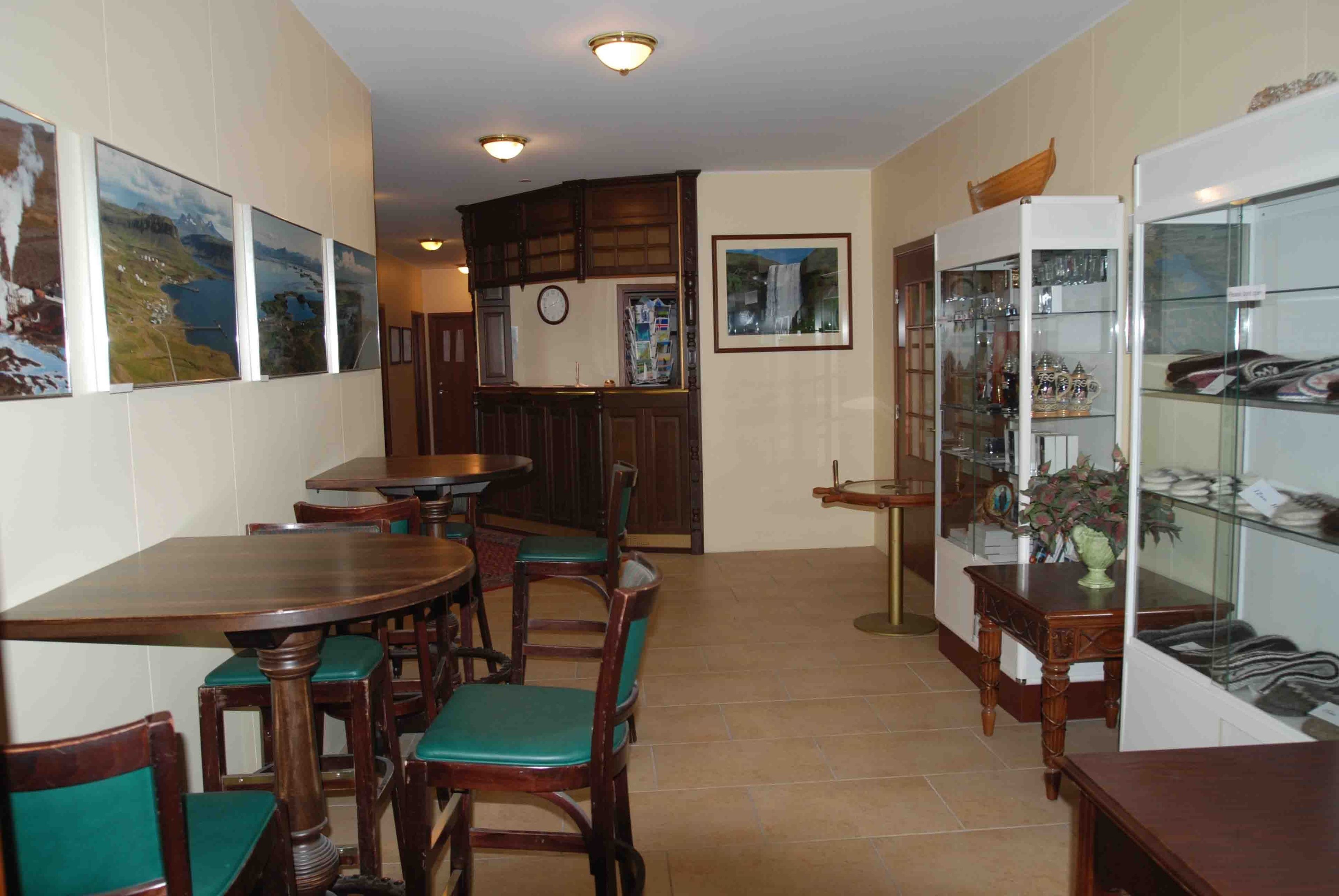 Een eetgedeelte met houten tafels en stoelen, een bar met een counter, en een vitrine met diverse artikelen.