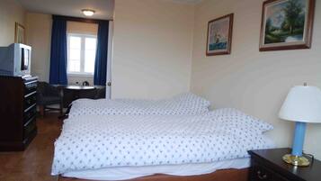 Una habitación de hotel con cama, escritorio, silla, cómoda y televisor.