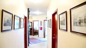 A hallway with framed pictures on the walls, a red carpet, and a door leading to another room. - Hotel Vogar (Vogar)