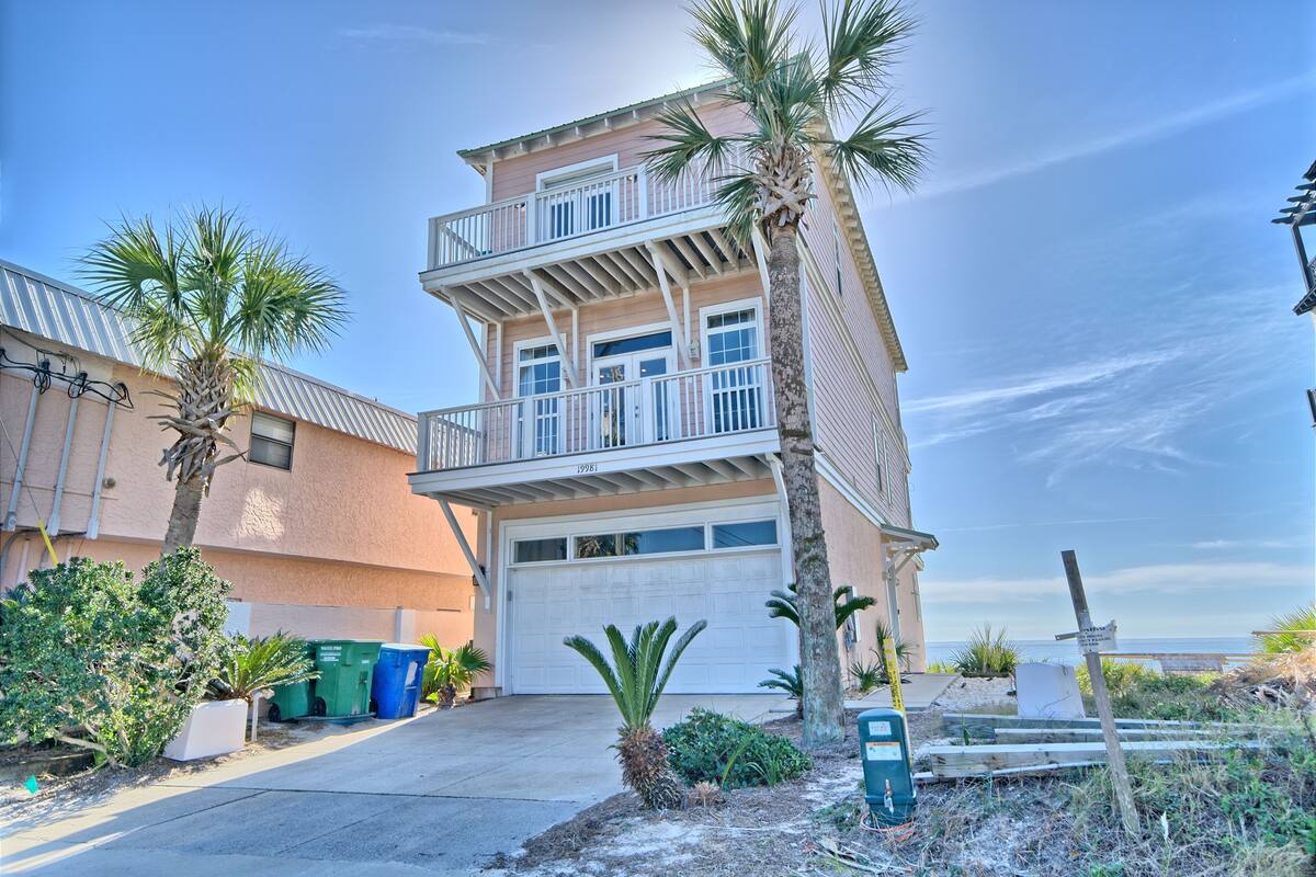 A two-story building with a garage, palm trees, and a clear sky.