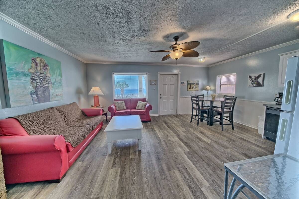 A spacious living area with a red sofa, a white coffee table, and a ceiling fan.