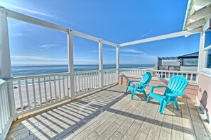 A covered outdoor area with a wooden deck, two turquoise Adirondack chairs, and a view of the ocean. - Pineapple Villas on Laguna Beach (Panama City Beach)