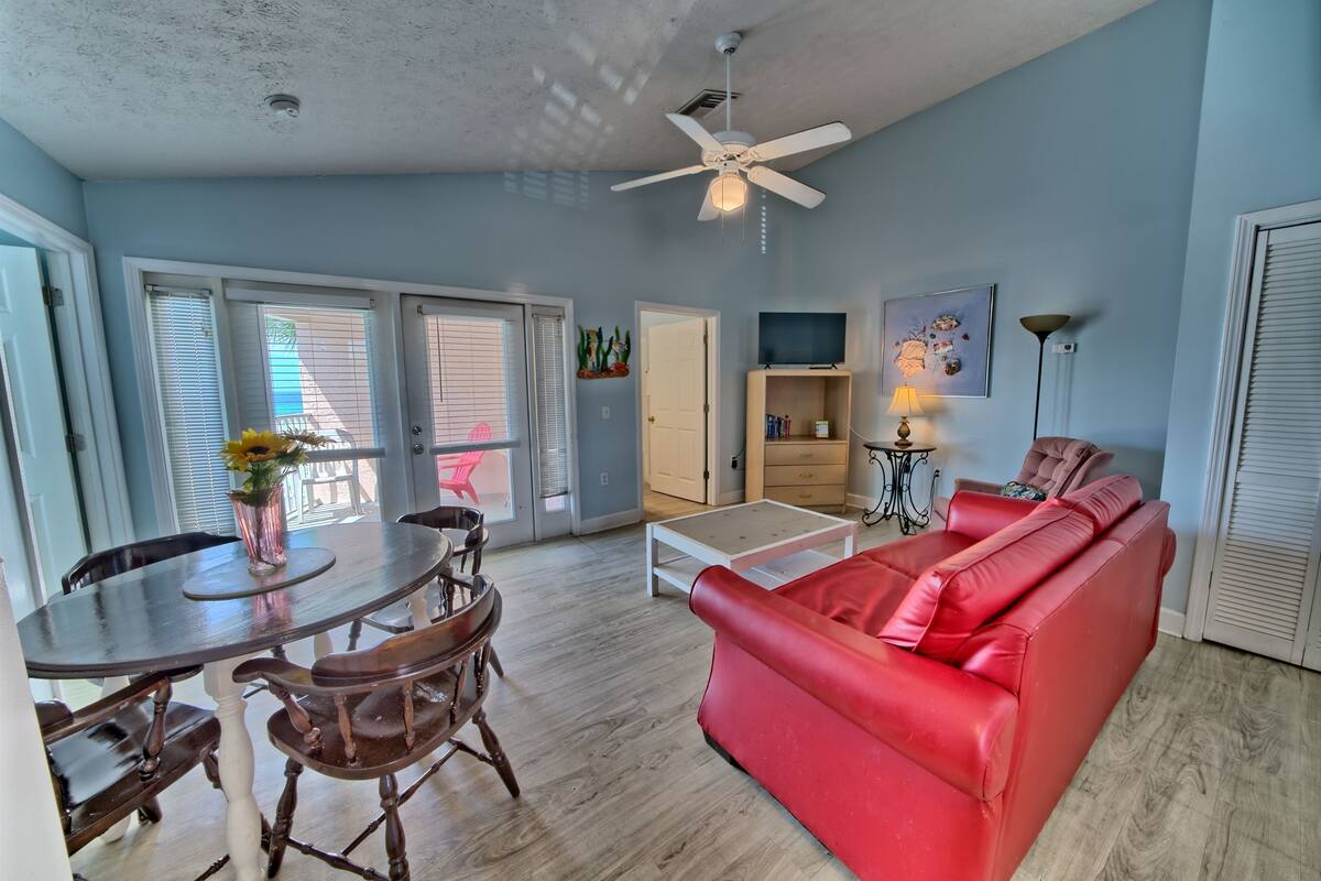 A living room with a red sofa, wooden dining table, and chairs.