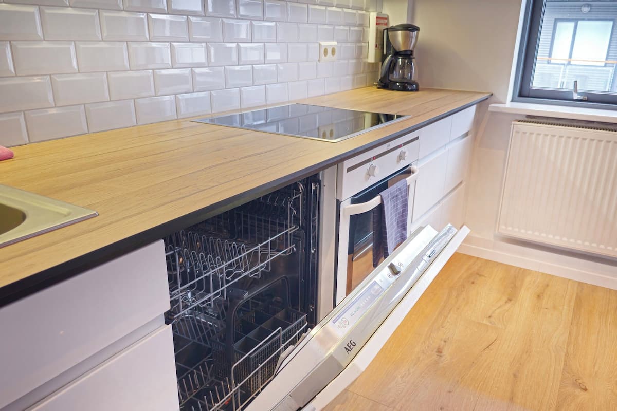 A kitchen with a dishwasher, oven, and a coffee maker on the counter.