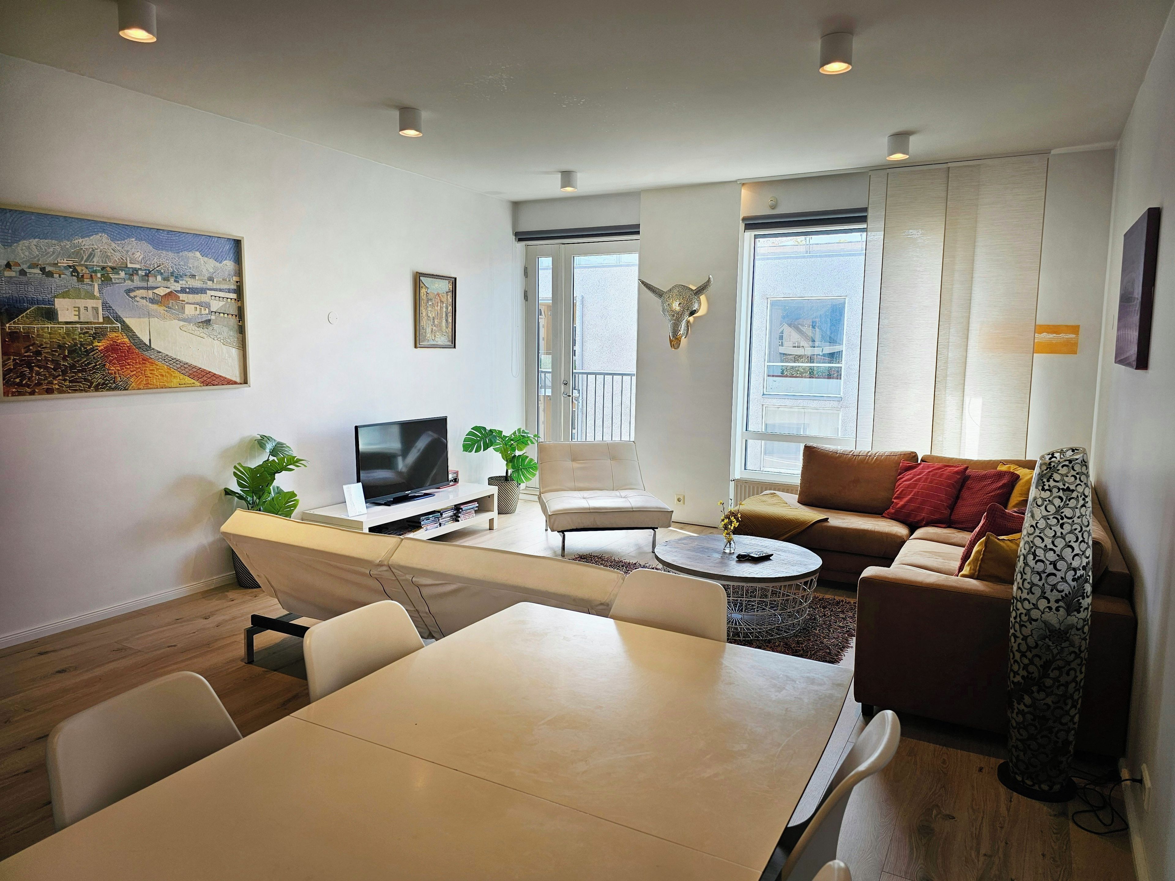 Een moderne woonkamer met een flatscreen televisie, een eettafel en een bank.