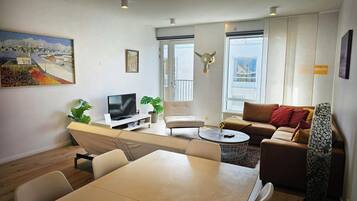 Een moderne woonkamer met een flatscreen televisie, een eettafel en een bank.