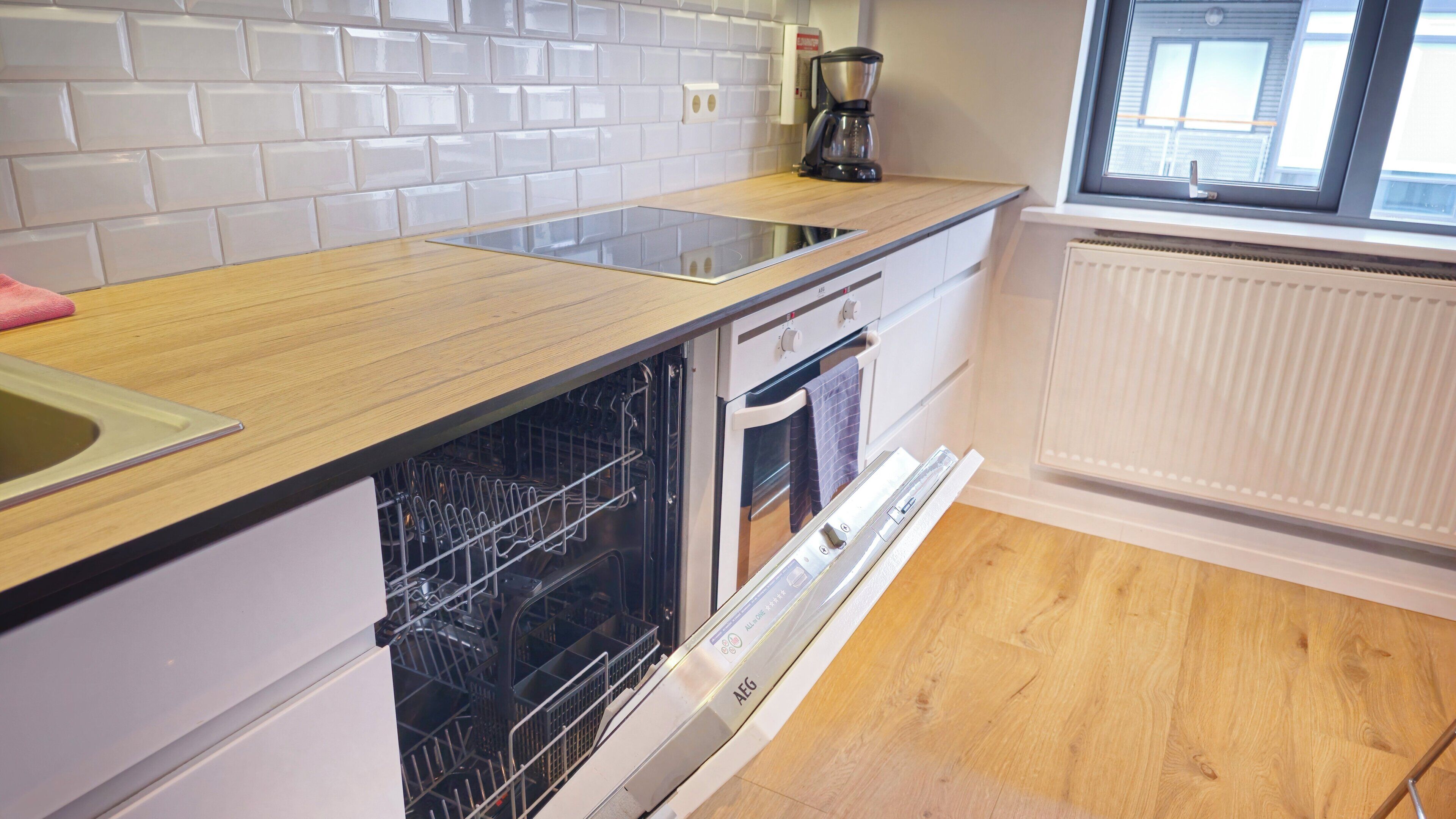 A kitchen with a dishwasher, oven, and a coffee maker on the counter.