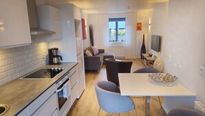 Una cocina compacta con estufa, cafetera y zona de comedor con mesa y sillas.