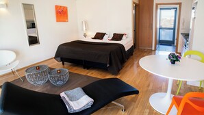 Un dormitorio moderno con cama, mesitas de noche, un sofá y un comedor.