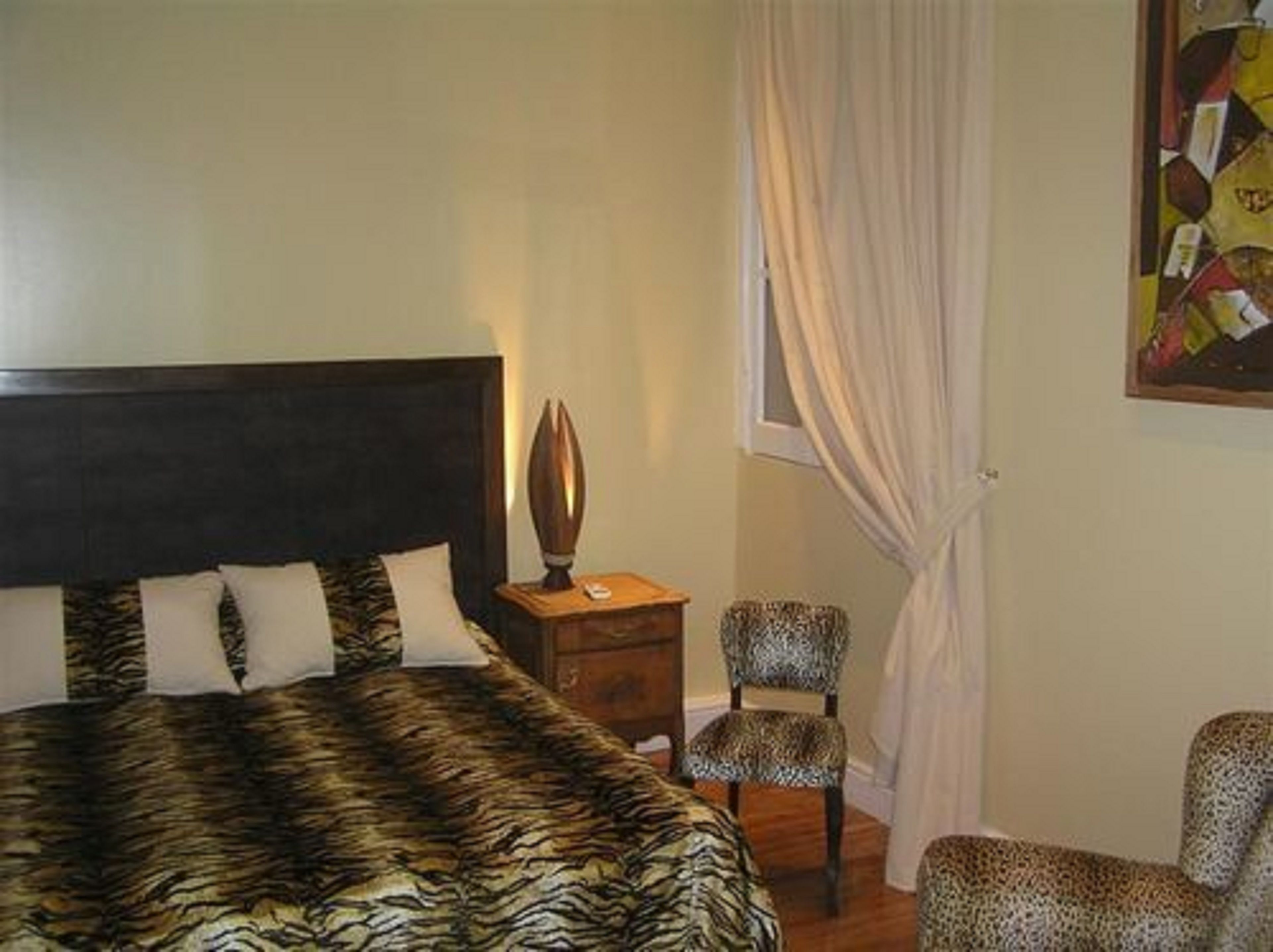 Ein Schlafzimmer mit einem Bett, einem Sessel, einem Nachttisch und einem Bild an der Wand.