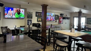 En restaurang med en inredning som inkluderar flera bord och stolar, ett biljardbord och sportrelaterade minnessaker på väggarna.
