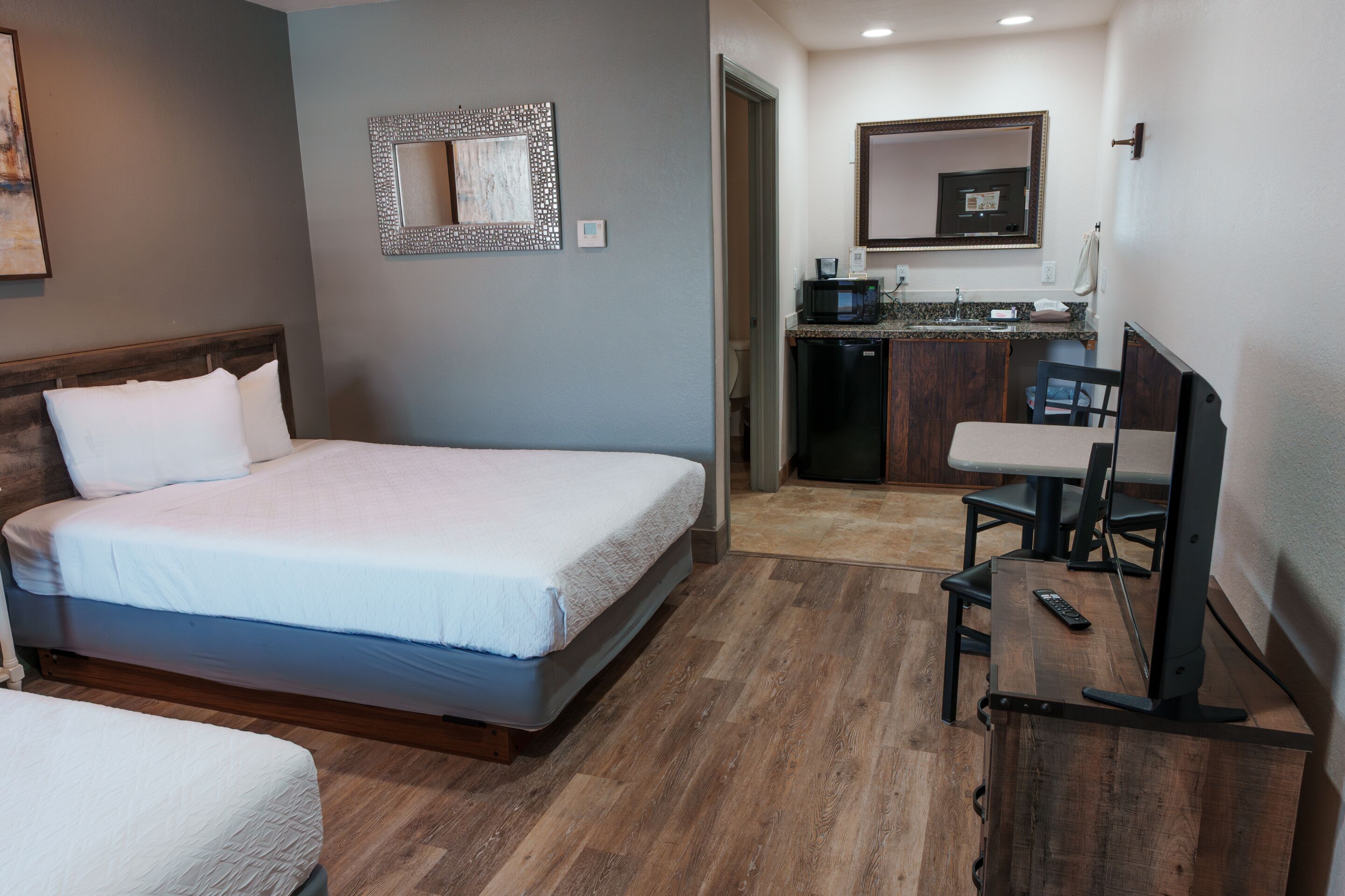 Ein Hotelzimmer mit einem Bett, einem Schreibtisch mit Computer, einer Mikrowelle und einer kleinen Küchenzeile.