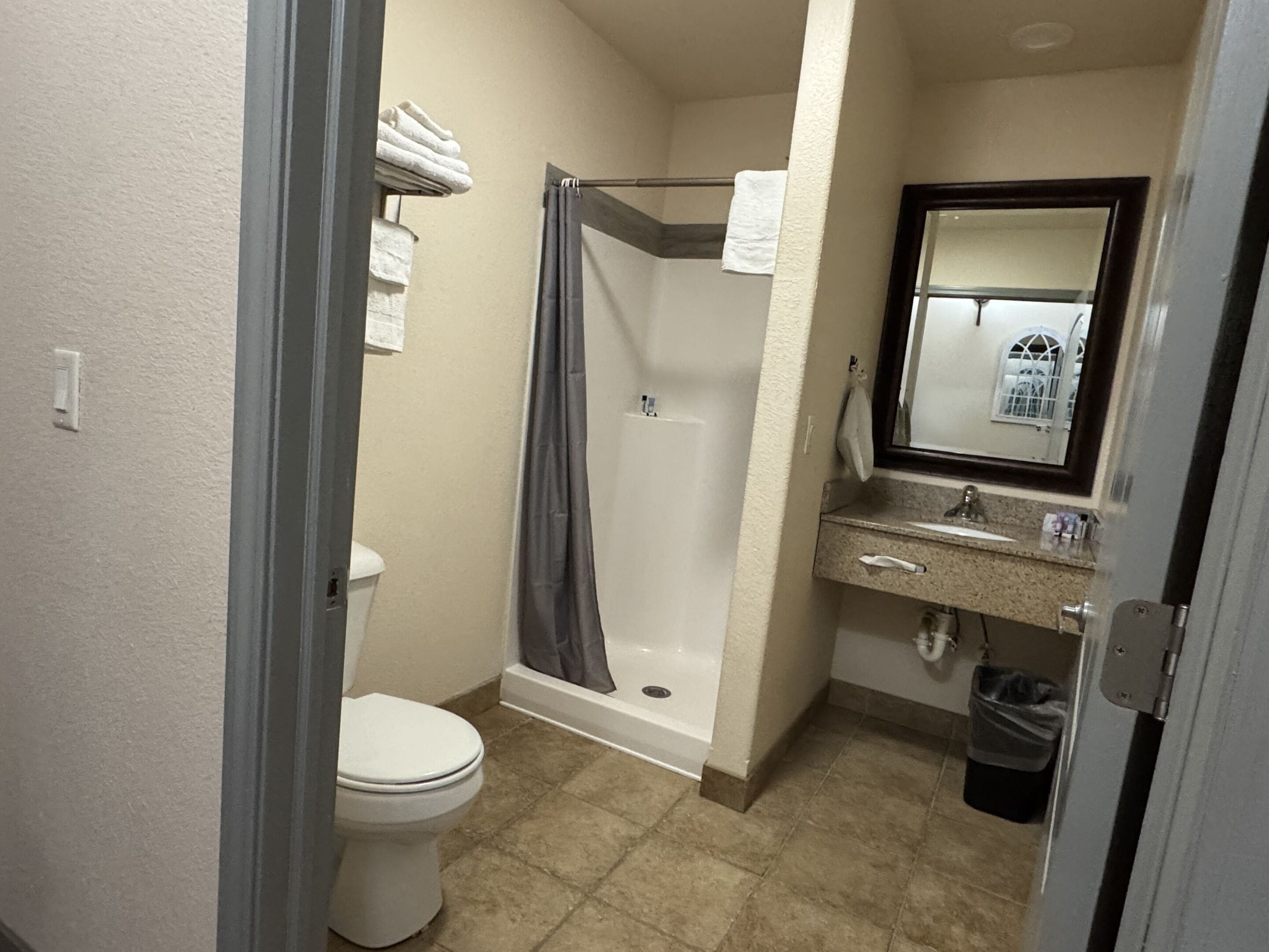 A bathroom with a toilet, shower, and sink.