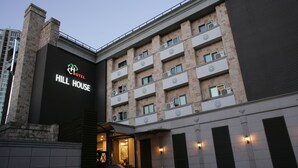 A hotel with a modern facade, multiple balconies, and a staircase leading to the entrance. - Hill house Hotel (Seoul)