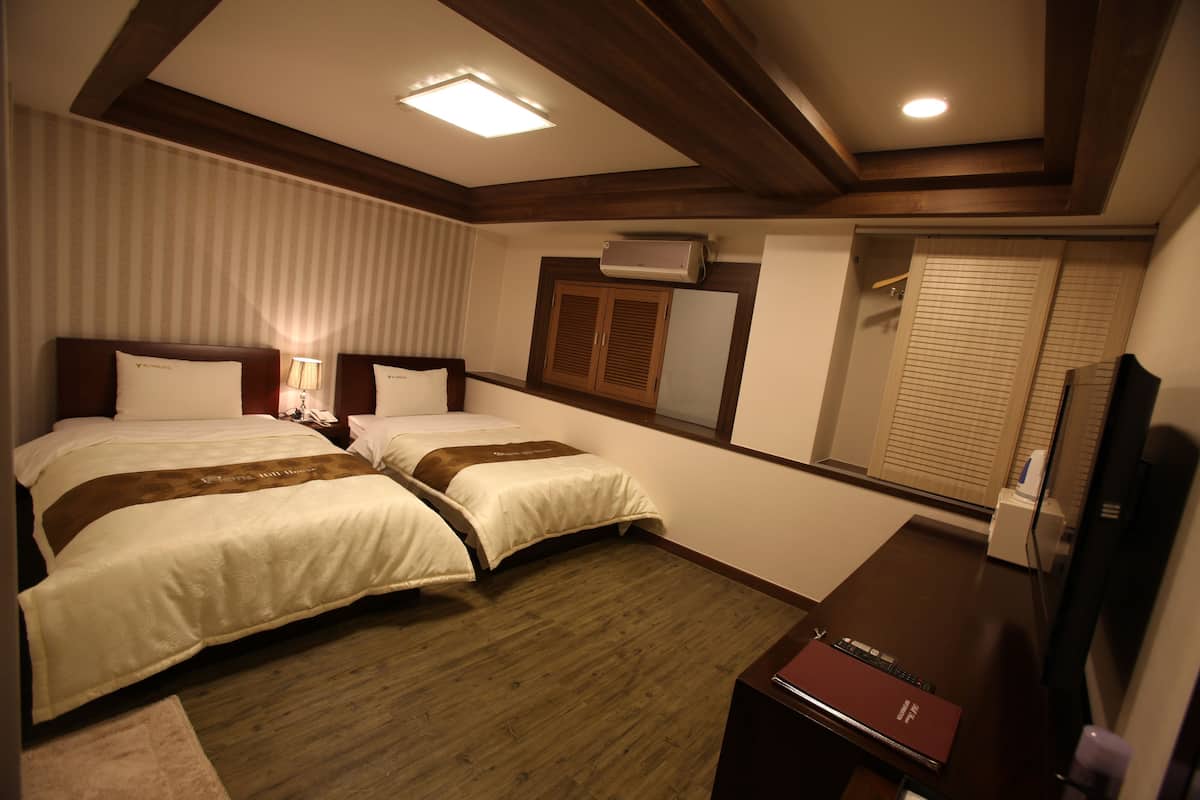 Habitación de hotel con dos camas, un escritorio, un televisor y un aire acondicionado.