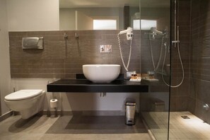 A modern bathroom with a glass-enclosed shower, a white sink, and a toilet.