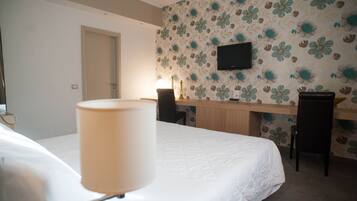 Une chambre d’hôtel avec un lit, un bureau, deux chaises, une télévision et une lampe.