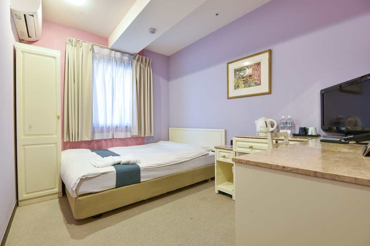 Une chambre d’hôtel avec un lit, un bureau, une télévision et une fenêtre avec des rideaux.