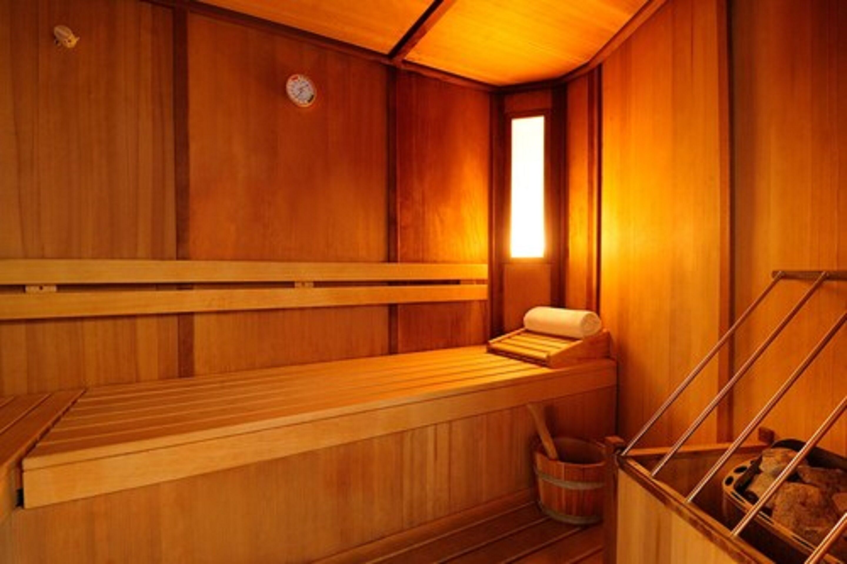 A wooden sauna with benches and a bench seat, a wooden wall, and a window.