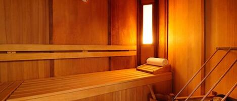 A wooden sauna with benches and a bench seat, a wooden wall, and a window.
