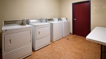 A laundry room with four white washers and dryers, a red door, and a sign indicating it's for guest use only.