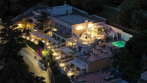Un edificio de varios pisos con zonas de estar al aire libre, una piscina y una entrada bien iluminada.